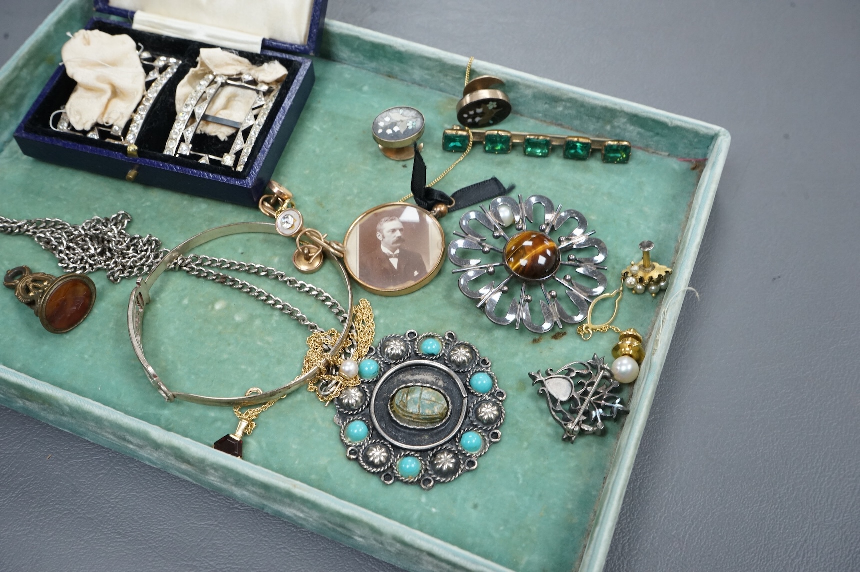 Assorted costume and other jewellery including a cased pair of paste buckles, agate set fob seal, a9ct pendant on a 9ct gold chain, Egyptian white metal bangle, a Scottish silver pendant, etc, housed in a mahogany work b